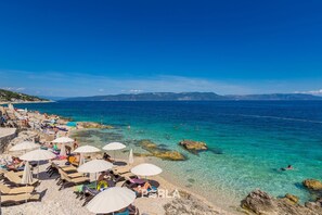 Una playa con agua turquesa cristalina, tumbonas y sombrillas.