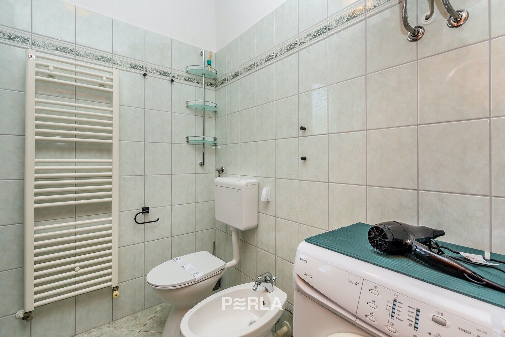 Une salle de bain équipée de toilettes, d’un bidet et d’un lave-linge.