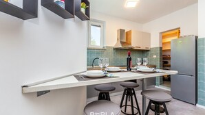 Una cocina moderna con una isla central, taburetes de bar y una estantería empotrada para vinos.