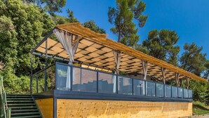 Un edificio moderno con fachada de madera, cerramiento de vidrio y una escalera de metal.
