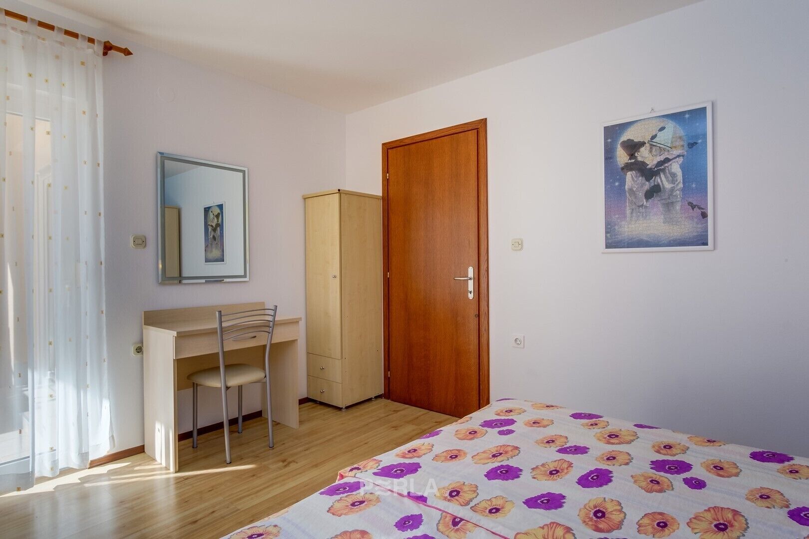 Ein Schlafzimmer mit Bett, Schreibtisch, Stuhl, Kleiderschrank und einem Bild an der Wand.