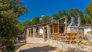 A rustic stone building with a wooden porch and two chimneys.