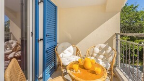 A balcony with wicker chairs, a table with drinks, and a blue door.