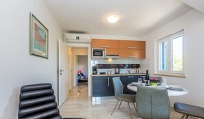 Una cocina moderna con una isla central, un comedor con una mesa redonda y sillas, y una unidad de aire acondicionado a la vista.