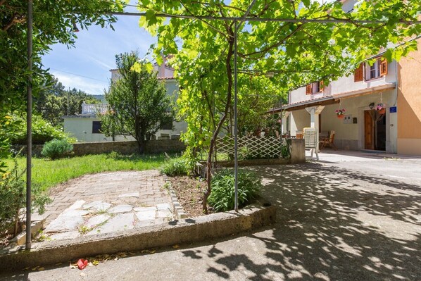 Une cour avec un chemin en pierre, un petit jardin et un bâtiment doté d’un balcon.