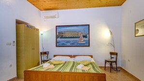 A bedroom with a wooden bed, a painting of a bridge, and a door. - Apartment casa MELITA with garden near Pula (Štinjan)