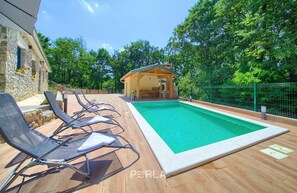 A swimming pool with lounge chairs, a wooden structure, and a stone building in the background. - Holiday house Capree with pool near beach Rabac (Ripenda Kras)