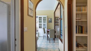 A hallway with a dining area, a bookshelf, and a door leading to another room. - Un Balcone Sulle Colline di Rapallo by Wonderful Italy (Rapallo)