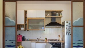 A kitchen with white cabinets, a stove, a sink, and a refrigerator. - Un Balcone Sulle Colline di Rapallo by Wonderful Italy (Rapallo)