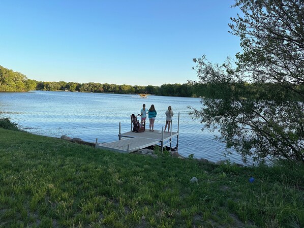 Un moll de fusta que s'endinsa en un llac tranquil sota un cel serè.