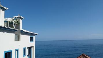 Un bâtiment situé sur la côte, avec des murs blancs et des touches de bleu, qui offre une vue sur la mer.