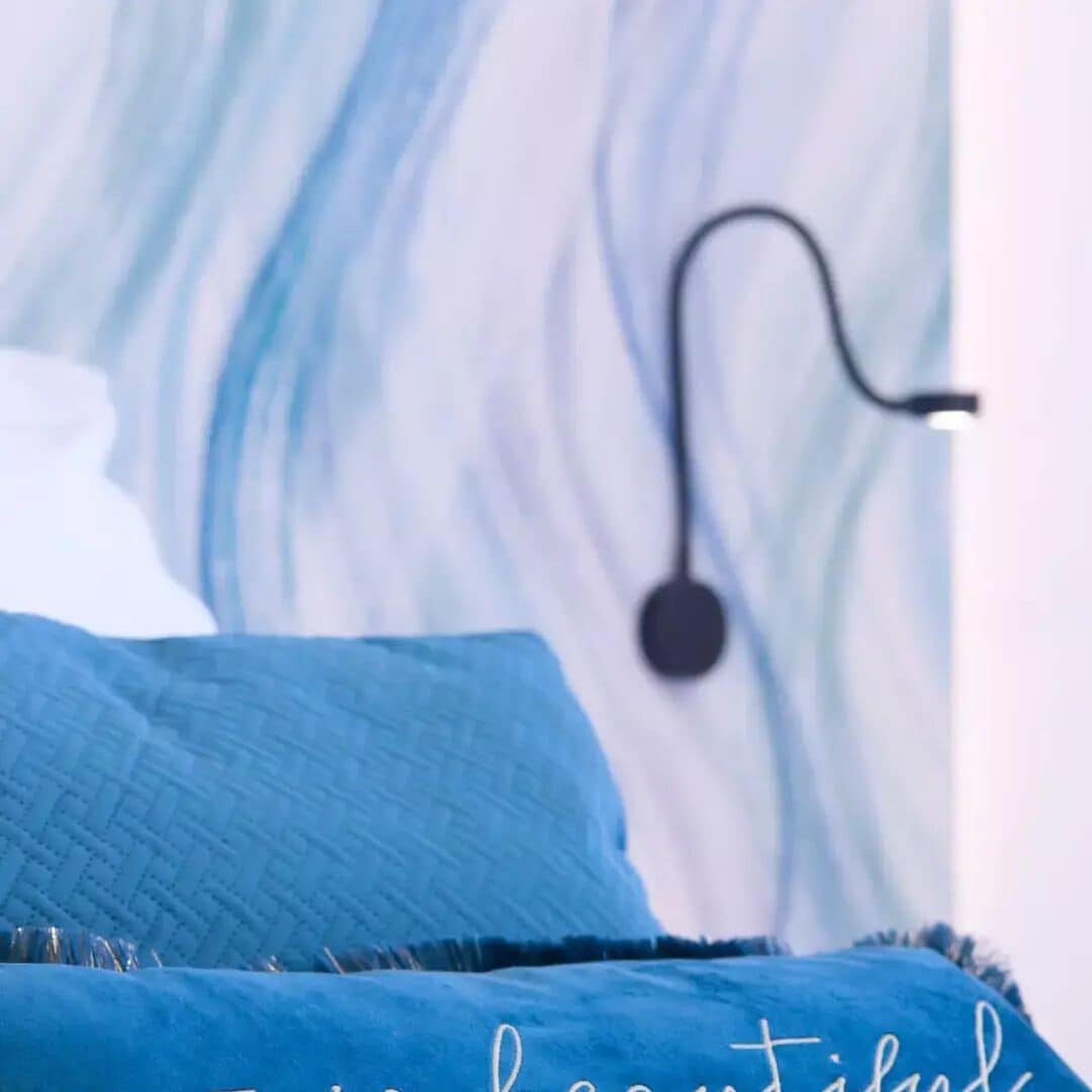 Ein Bett mit blauer Bettwäsche und eine Wand mit einem abstrakten blauen und weißen Muster.