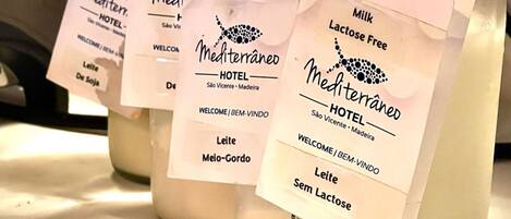 Four bottles of milk with labels indicating different types, including lactose-free and half-fat options, displayed on a table.
