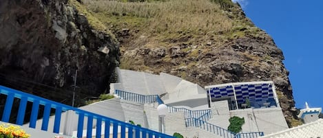 Una escalera que sube hacia un acantilado, con vistas al cielo y nubes.