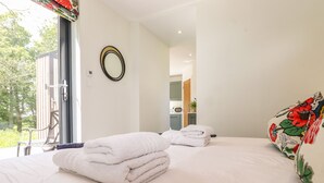 A bedroom with two beds, a large window, and a view of the outdoors. - Brow Wood Cabin (Penrith)