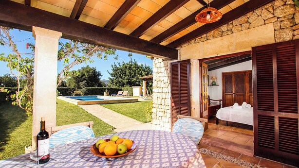 A covered outdoor seating area with a table set for two, a bottle of wine, and a bowl of fruit. - Casita Fontxica - Two Bedroom Villa, Sleeps 4 (Mallorca)