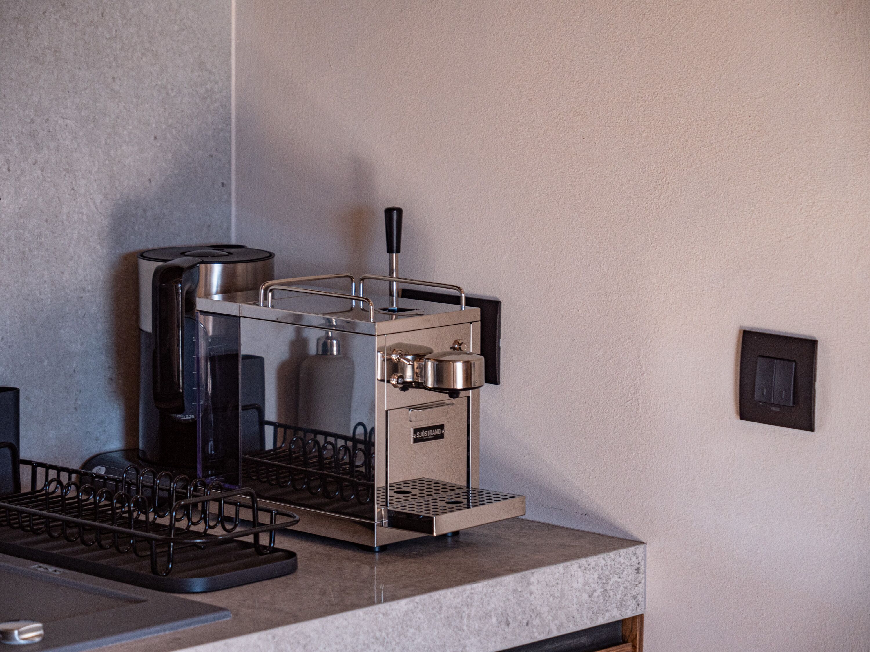 A commercial espresso machine with a metal frame, a water tank, and a coffee dispensing area.