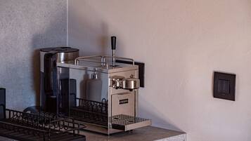 A commercial espresso machine with a metal frame, a water tank, and a coffee dispensing area.