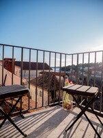 Un balcón con vistas a un paisaje urbano, una mesa con una botella y una silla.