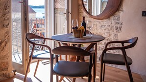 A dining area with a round table, two chairs, a bowl of grapes, and a bottle of wine. - Villa Porta Maestra (Hvar)