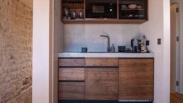 Una cocina moderna con pared de piedra, armarios de madera, microondas integrado y cafetera.