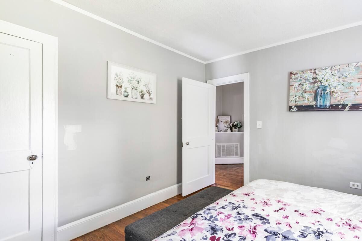 A bedroom with a bed, a door, and a hallway leading to a bathroom.