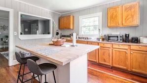 A kitchen with wooden cabinets, a marble countertop island, and bar stools. - {Sunflower Morning} A cozy farmhouse-style house in South End HOT TUB! (Charlotte)