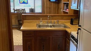 Una cocina compacta con armarios de madera, un lavamanos, una estufa y un ventilador de techo.