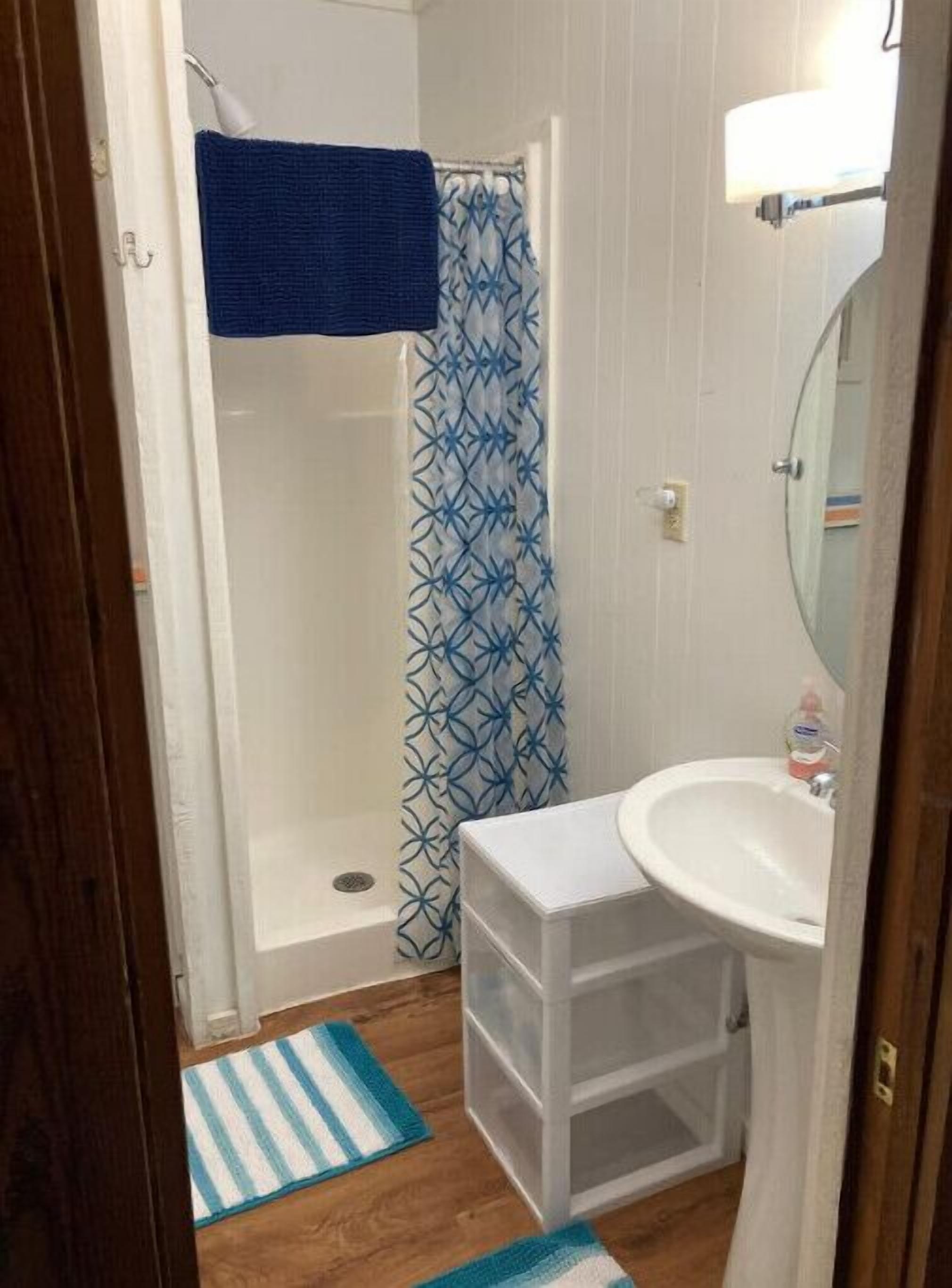 A small bathroom with a shower, a sink, and a mirror.