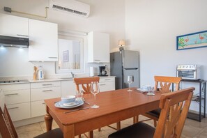 Una cocina moderna con armarios blancos, una mesa de comedor de madera y un horno pequeño.