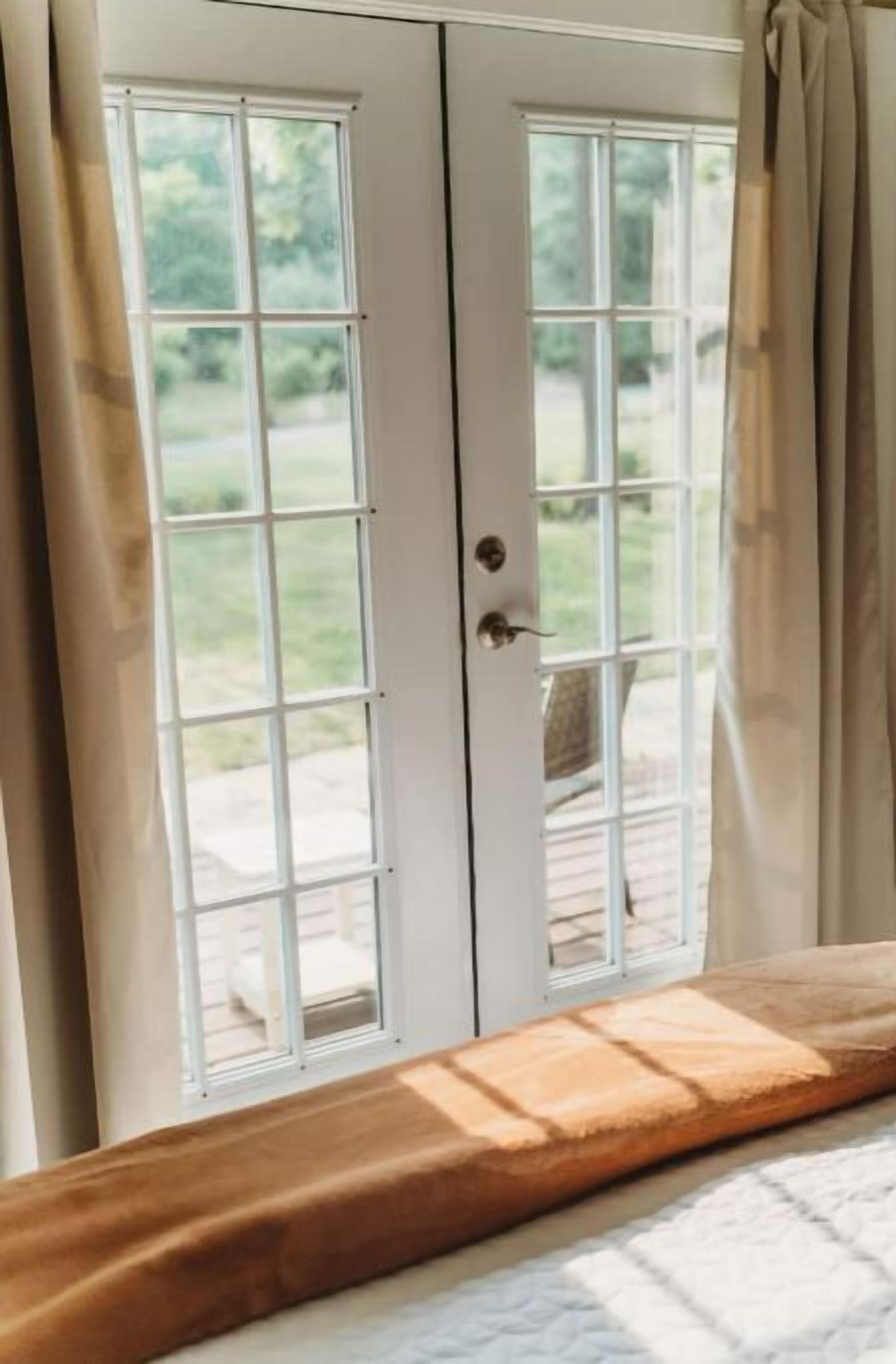 Une chambre à coucher avec un lit, une fenêtre avec des rideaux et une vue sur l’extérieur.