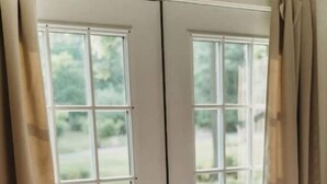 A bedroom with a bed, a window with curtains, and a view of the outdoors. - Cottage near water park, golf and skiing at Massanutten Resort! (McGaheysville)