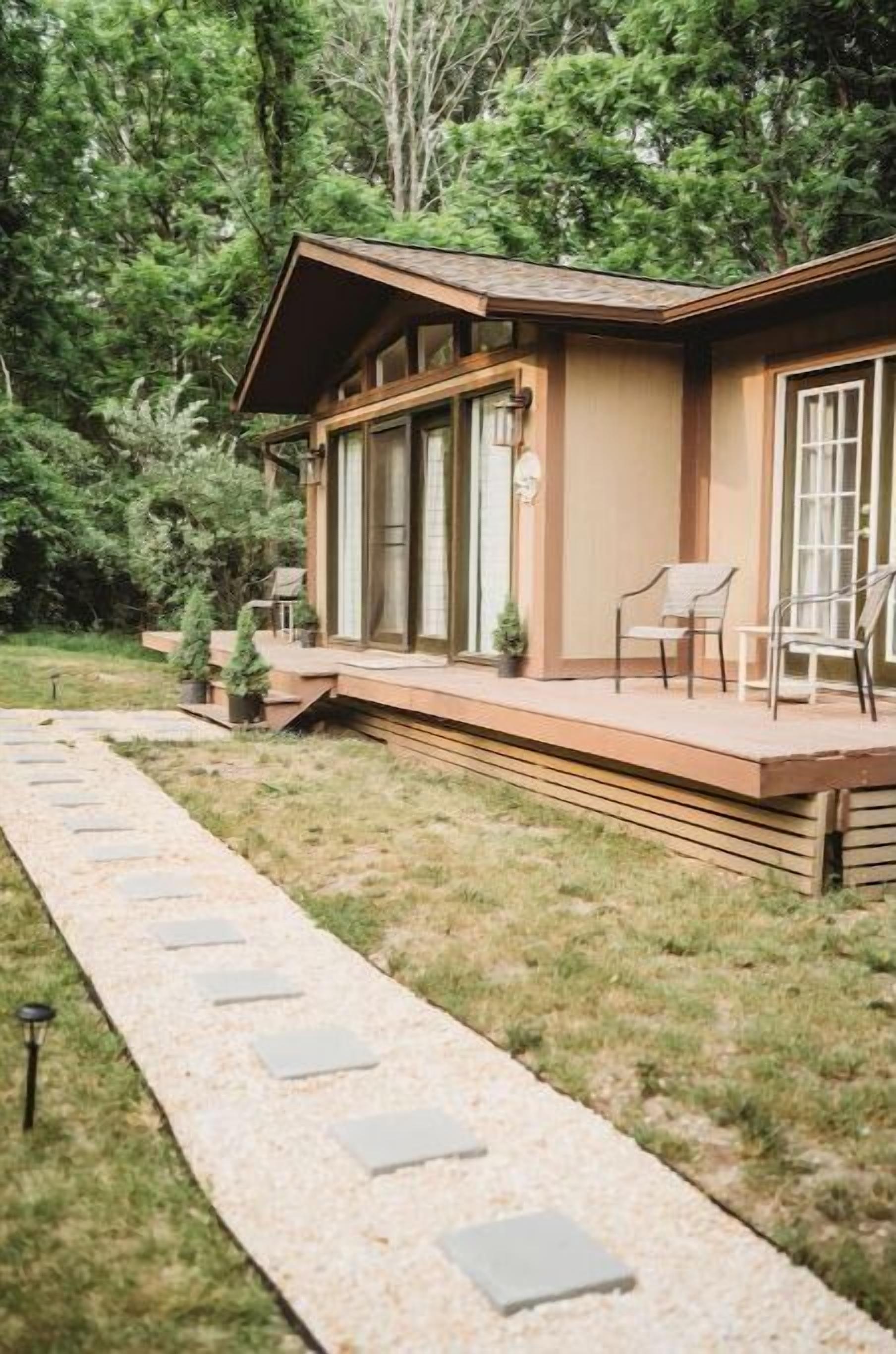Une cabane en bois dotée d’une terrasse, entourée d’arbres.