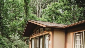 A wooden cabin with a deck, surrounded by trees. - Cottage near water park, golf and skiing at Massanutten Resort! (McGaheysville)