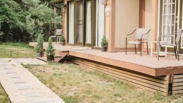 Une cabane en bois dotée d’une terrasse, entourée d’arbres.