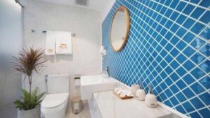 Un baño con inodoro, lavabo, espejo y pared con azulejos azules.