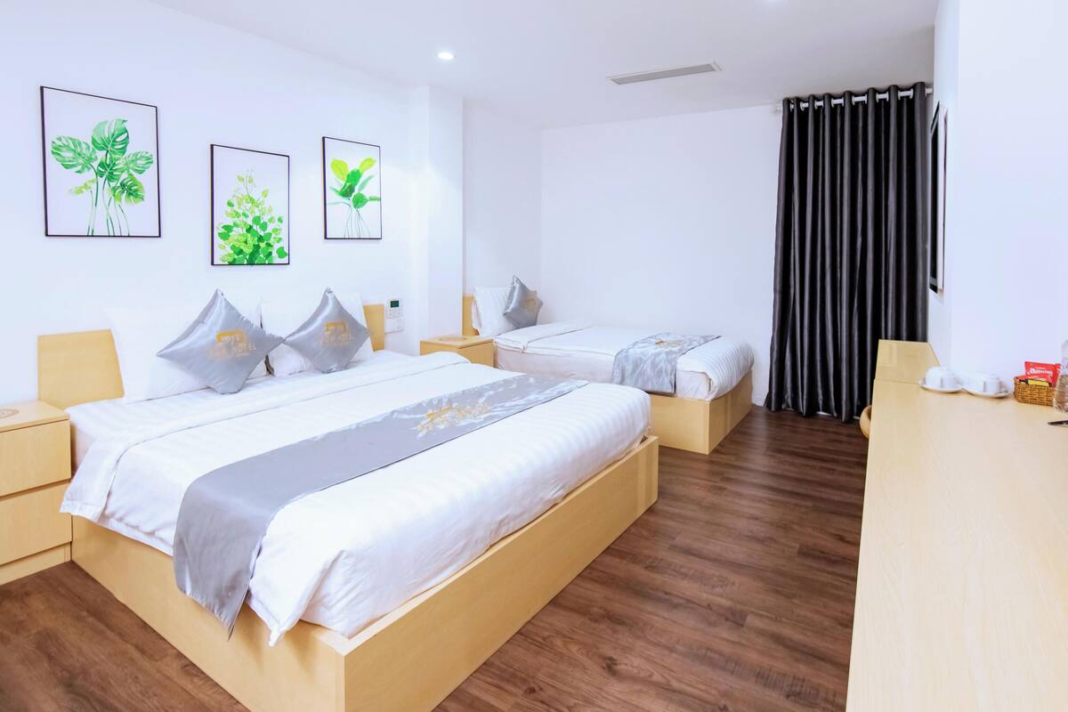 A hotel room with two beds, a TV, a desk, and artwork on the wall.