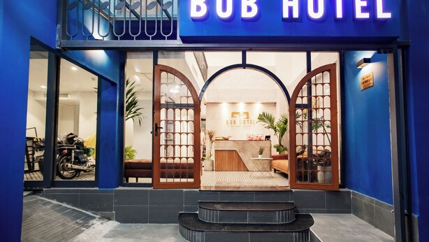 Exterior del Hotel Bob con fachada azul, un área de recepción visible y una motocicleta estacionada afuera.