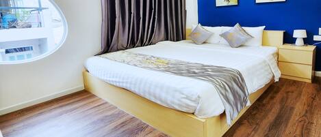 A bedroom with a bed, a bedside table, a lamp, and a view of the outside.