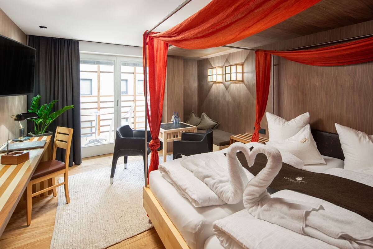Una habitación de hotel con una cama, un escritorio, una silla, un televisor y una ventana.