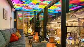 A modern interior with a sofa, tables, and a colorful ceiling. - Goldener Adler (Ischgl)