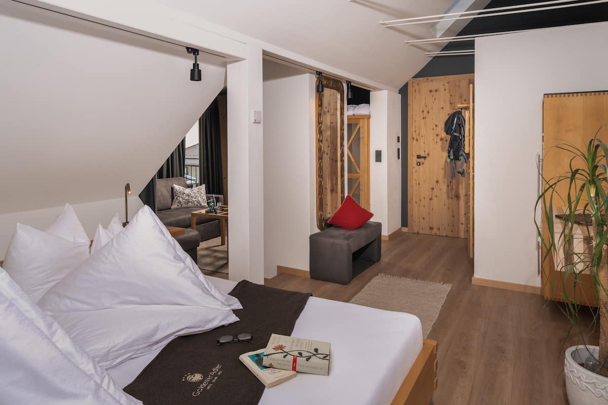 Habitación de hotel moderna con cama, un pequeño rincón de estar y una escalera que sube a un altillo.