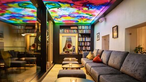 A cozy living area with a sofa, two small tables, and a bookshelf. - Goldener Adler (Ischgl)
