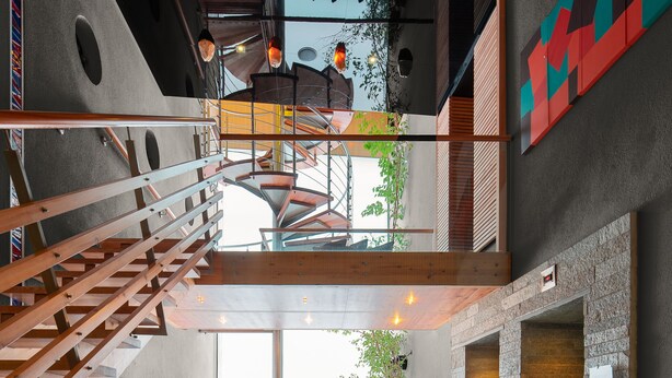 A modern interior with a central circular water feature, a staircase, and a seating area with cushions. - Goldener Adler (Ischgl)