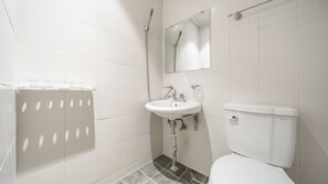 Un baño con lavamanos, inodoro y ducha blancos.