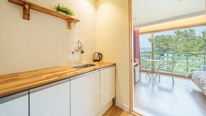 A modern kitchen with a wooden countertop, white cabinets, and a built-in sink. A small plant is on a shelf above the countertop. - Gangneng Badapunggeong Pension (Gangneung)