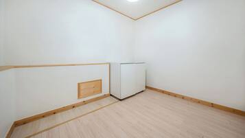 Una habitación con piso de madera, paredes blancas y un armario de esquina.