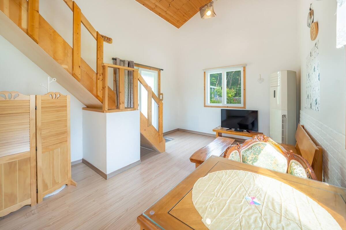 A spacious room with a wooden staircase, a television, and a bed.