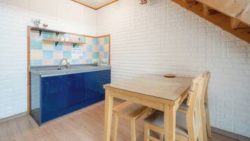 A compact kitchen with a blue cabinet, a wooden table, and a chair.