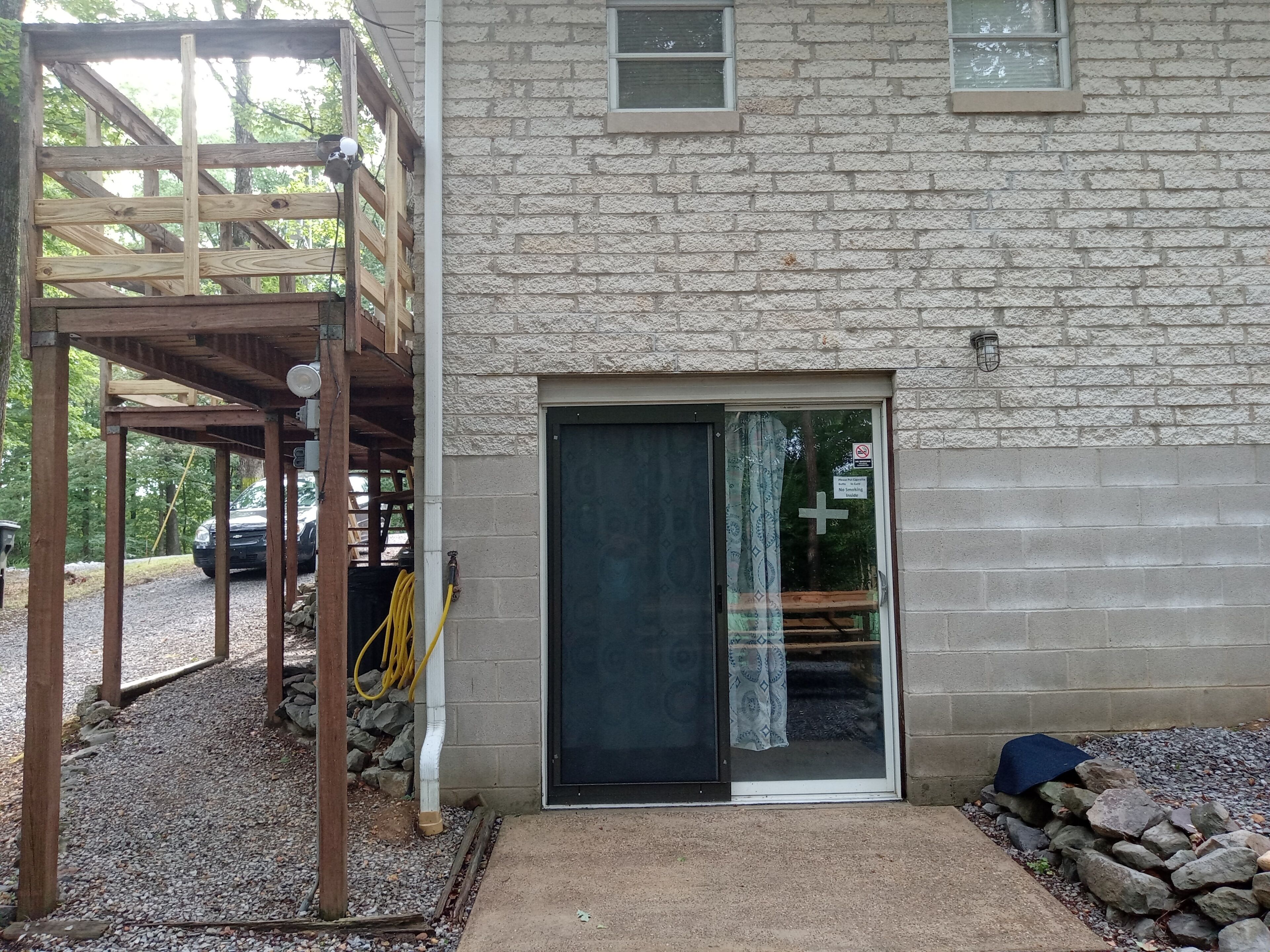 A building with a stone facade, a wooden deck, and a covered outdoor area.
